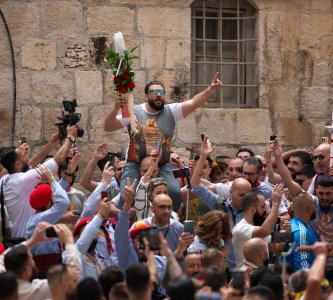 A crowd of Christian Jerusalemites in the Church of the Holy Sepulchre courtyard; their arms are raised in supplication, April 4, 2023.