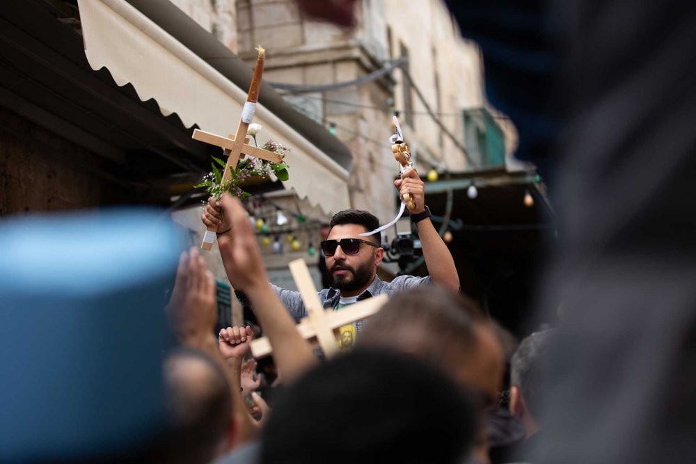 A young man in a crowd lifts a cross during an Easter procession at the Church of the Holy Sepulchre in Jerusalem, April 4, 2023.