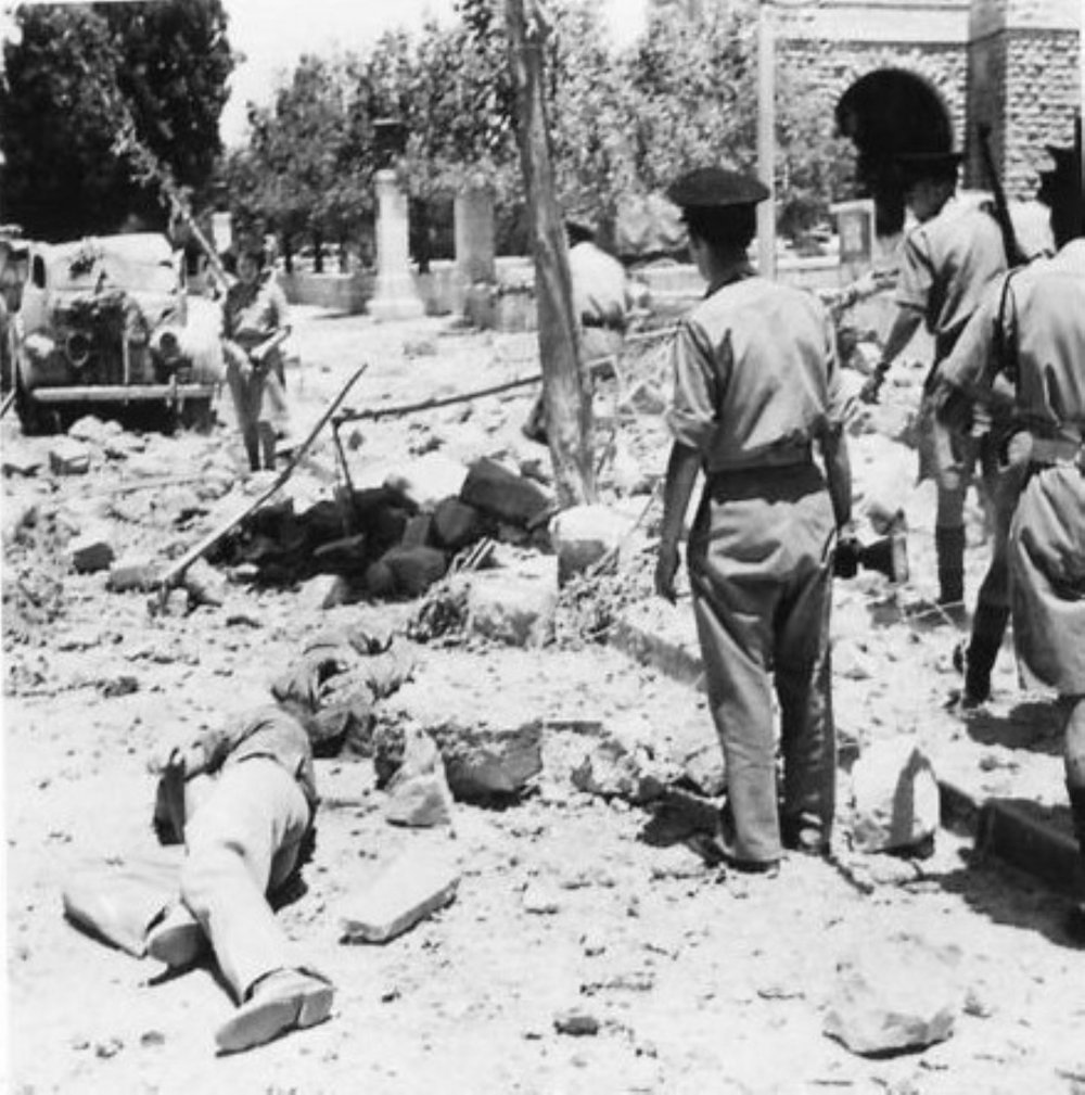 Constables of the Palestinian Police at the bombed King David Hotel search for victims. In the foreground are two bodies. 