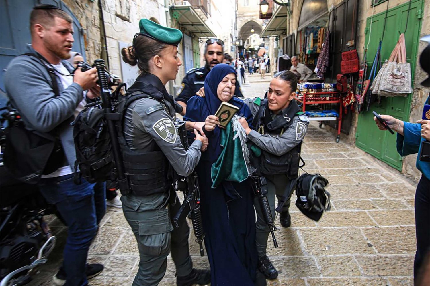 A Palestinian woman with a Quran in her hand is arrested by Israeli officers in East Jerusalem in October 2023.