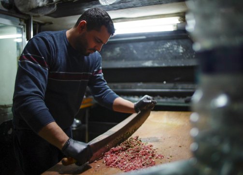 A cook prepares meat using only his hands at al-Karawan restaurant, in the shadow of Israel's Separation Wall, 2021