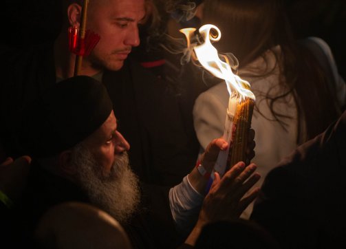A priest passes the holy flame to worshippers in the Church of the Holy Sepulchre on Great Saturday, April 15,2023.