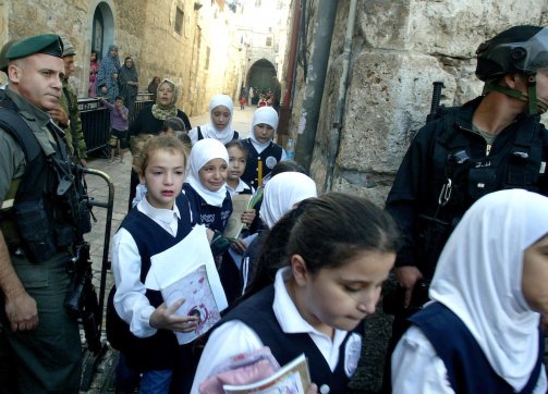Fearful Palestinian schoolchildren walk past Israeli riot police during clashes near the al-Aqsa Mosque compound in Jerusalem’s Old City on October 25, 2009.