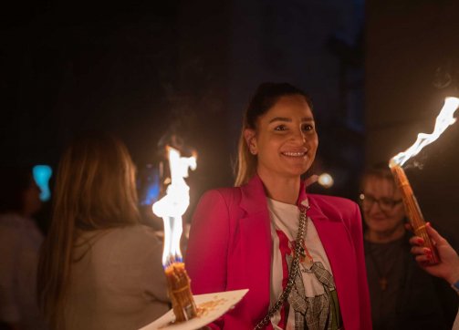 A smiling woman holds a torch during the Orthodox Holy Fire ceremony in the Church of the Holy Sepulchre, April 4, 2023.