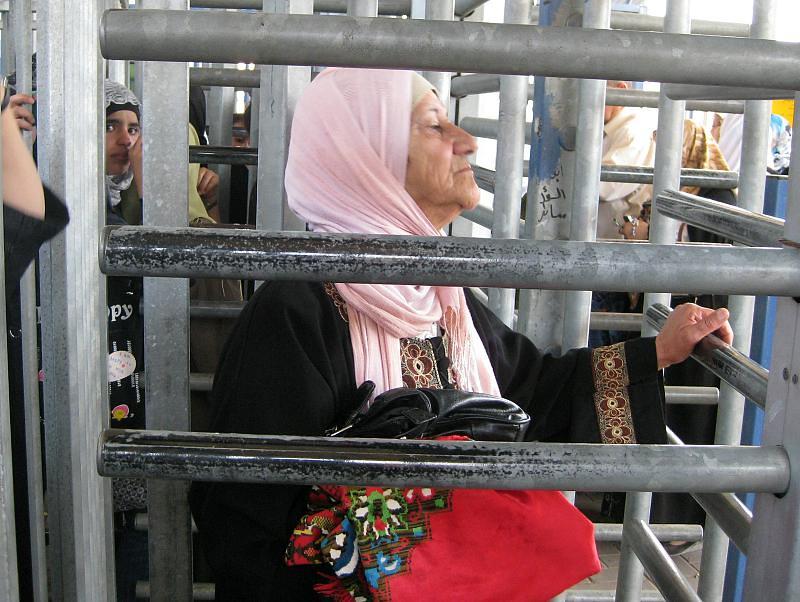 An elderly woman passes through the high metal turnstiles at Qalandiya checkpoint