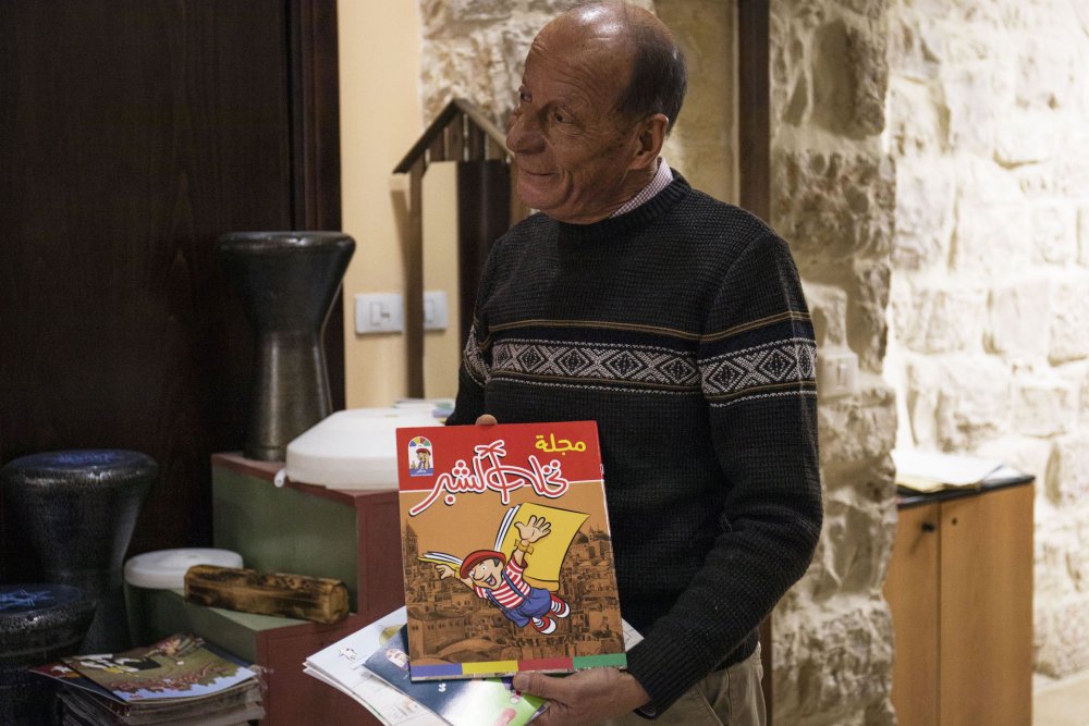 Yacoub Abu Arafeh holds up a children’s magazine named after his Nakhleh Esheber puppet show