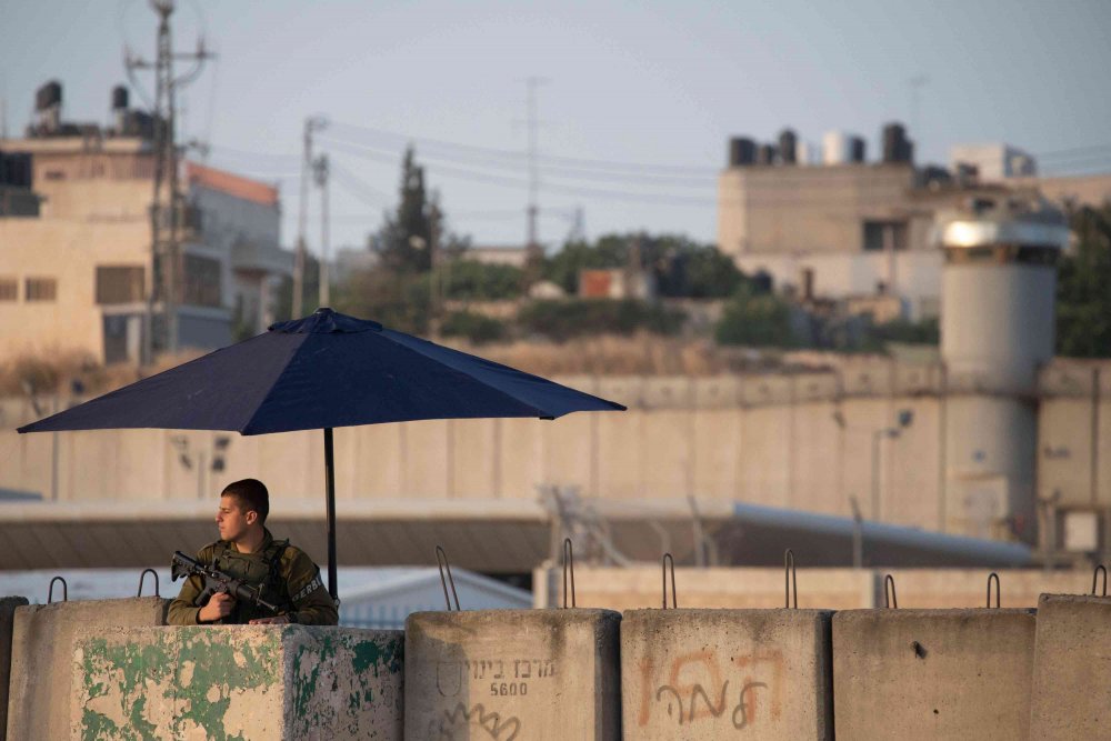 An Israeli soldier guards the entrance to Qalandiya checkpoint, Palestinians' main entryway to Jerusalem, 2019