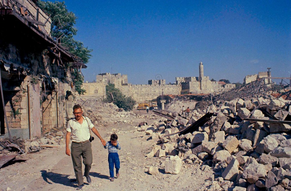 A father and son walk through destroyed areas of Jerusalem at the end of the 1967 War