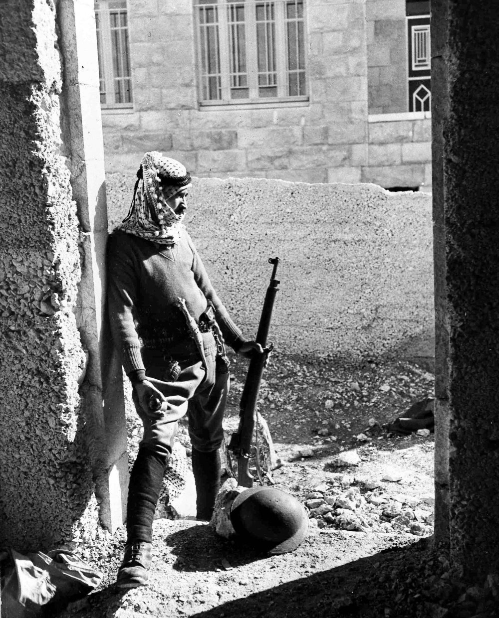 An armed Arab volunteer stands guard near Upper Baq‘a, in Jerusalem’s New City, 1948