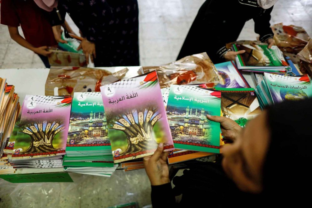 Palestinian parents distribute textbooks to schoolchildren in Shufat refugee camp 