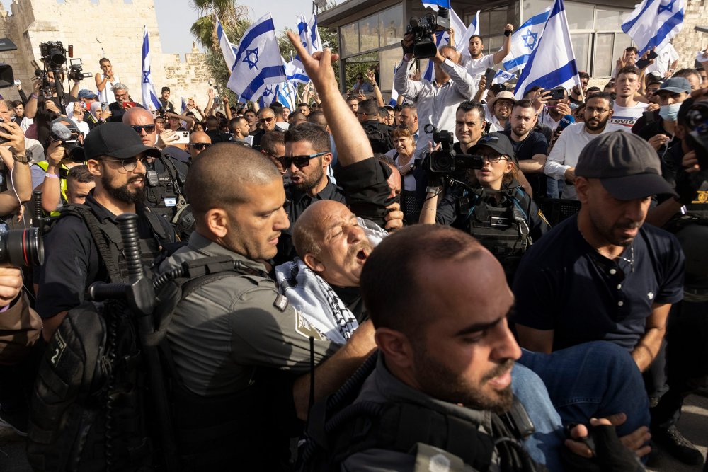 A Palestinian man holds up a victory sign while being restrained by Israeli police outside Damascus Gate at the Flag March, 2022.