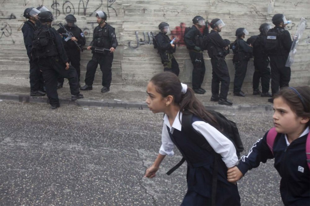 Palestinian schoolgirls rush past Israeli riot police in East Jerusalem