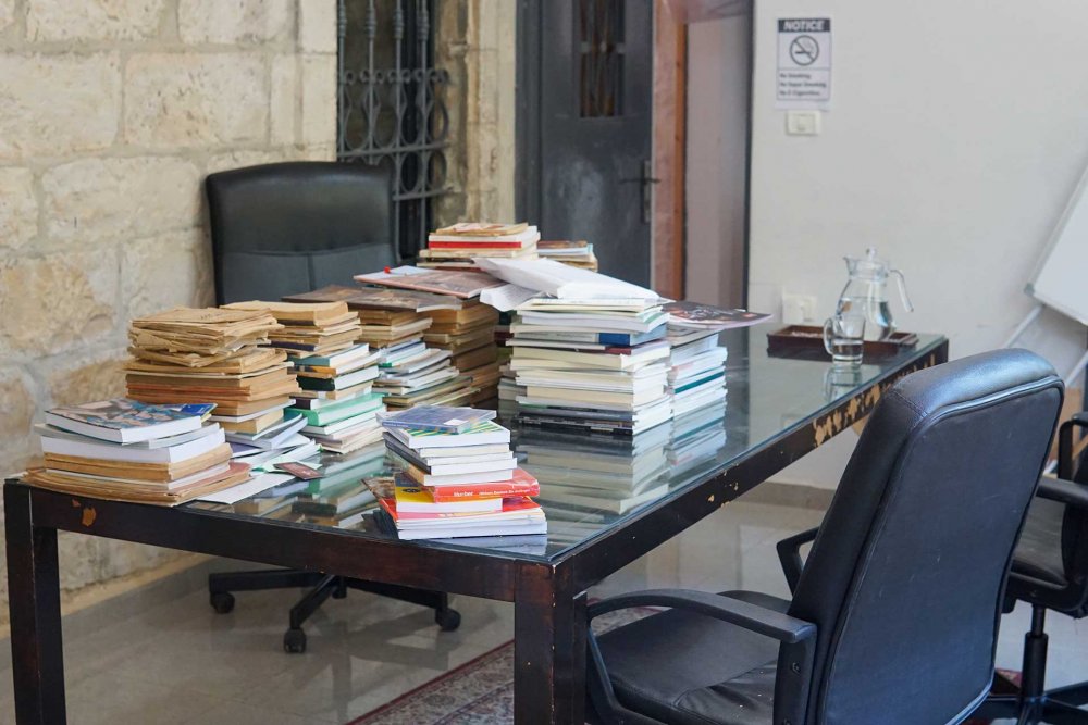 A table covered with stacks of books, sent to Khazaaen for archiving