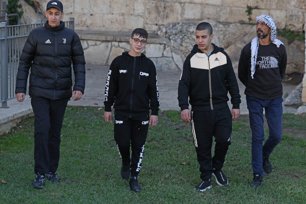Palestinian teenagers (left to right) Mohamed, Ahmad, and Moataz Al-Salaymeh, cousins imprisoned by Israel before their release as part of an exchange deal, walk next to Ahmad’s father in Ras al-Amud, East Jerusalem, December 12, 2023.
