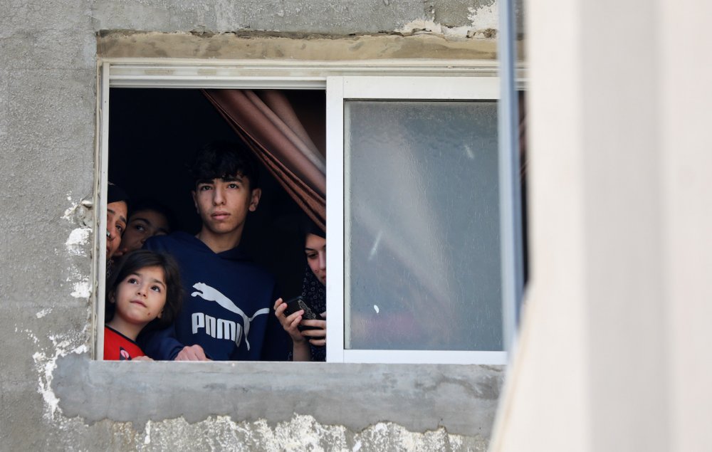 Palestinians somberly watch from their home’s window a funeral procession in Gaza City on May 9, 2023.