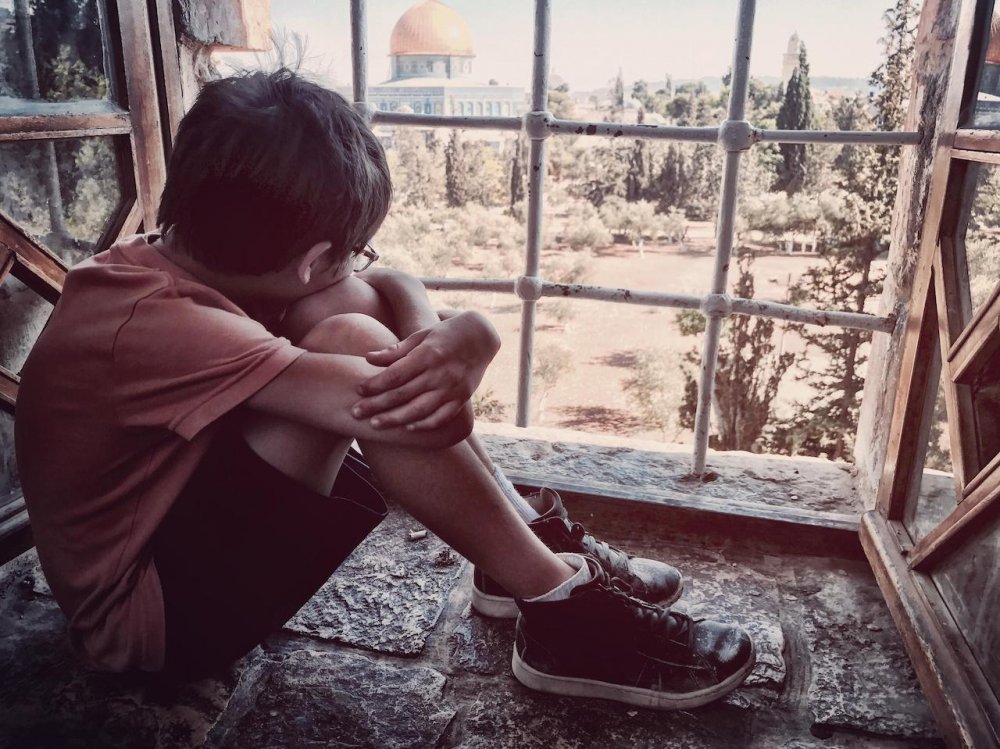 A young boy looks out a barred window at the Dome of the Rock in Jerusalem’s Old City.