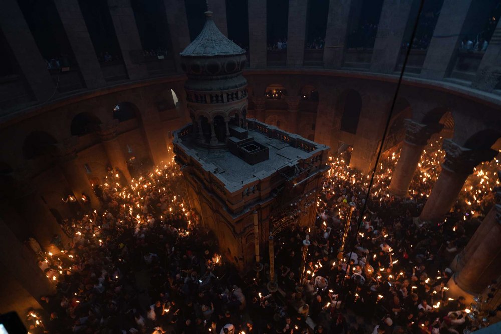 The faithful pass lit torches received from the Holy Fire ceremony in the Church of the Holy Sepulchre, April 4, 2023.