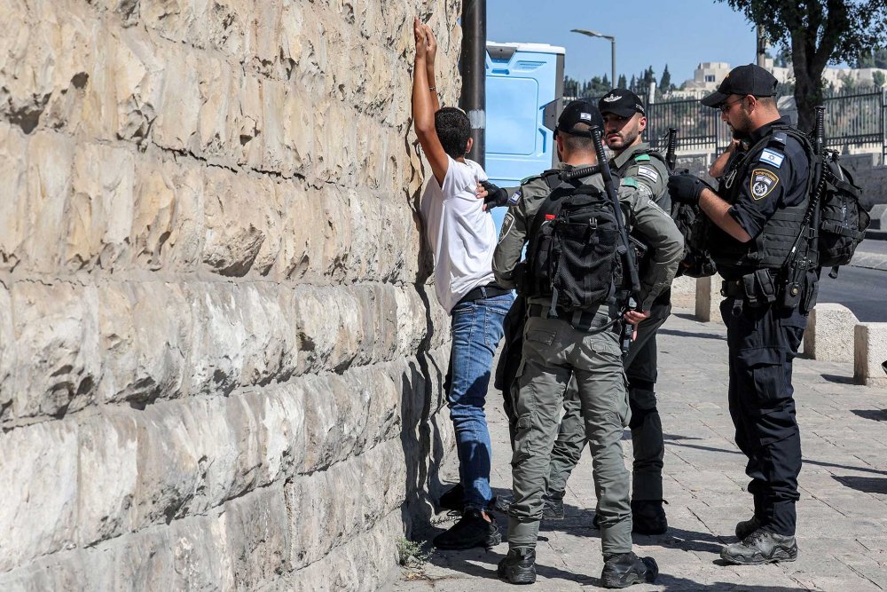 Israeli border guards and police search a Palestinian youth outside the Lions’ Gate to the Old City of Jerusalem, October 13, 2023.
