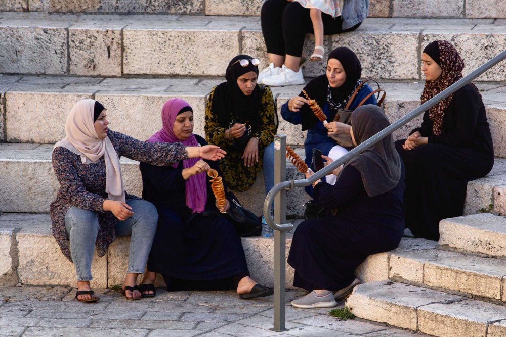 Palestinian women enjoy a moment together eating a street snack on the steps of the Bab al-Amud Plaza, August 20, 2021.