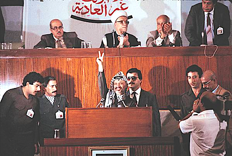 Abd al-Hamid al-Sayih seated above Yasser Arafat as he declares Palestine’s independence in Algeria in November 1988