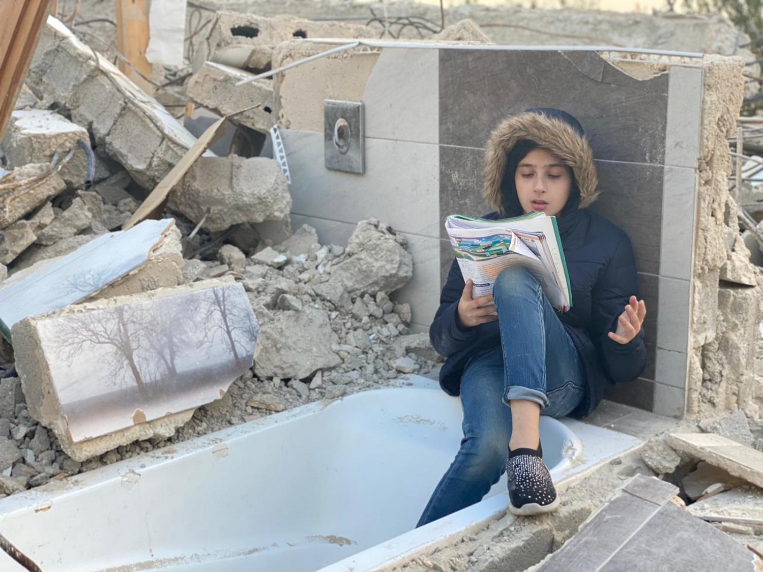 Sophie does her homework in the rubble of her demolished house in Jabal Mukabbir, Jerusalem