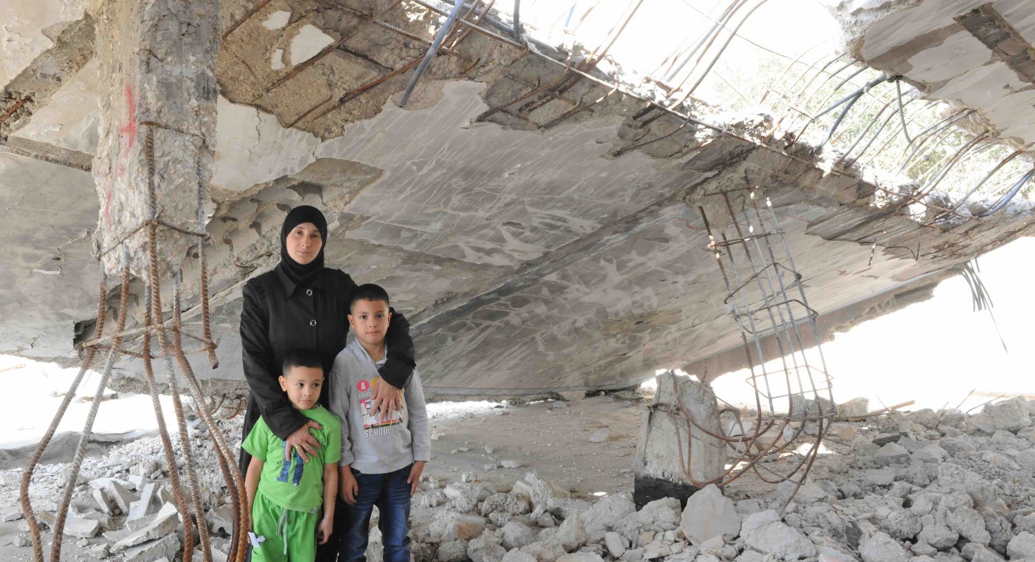 Nadia Abu Jamal stands with her two sons in her demolished home in Jabal Mukkabir, East Jerusalem