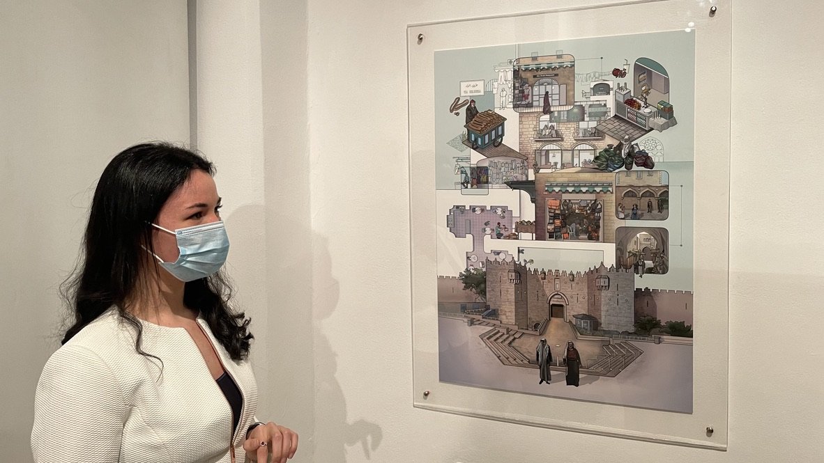 Yasmine Mansour stands in front of her digital painting "The City as Museum" at al-Hoash's visual arts exhibition