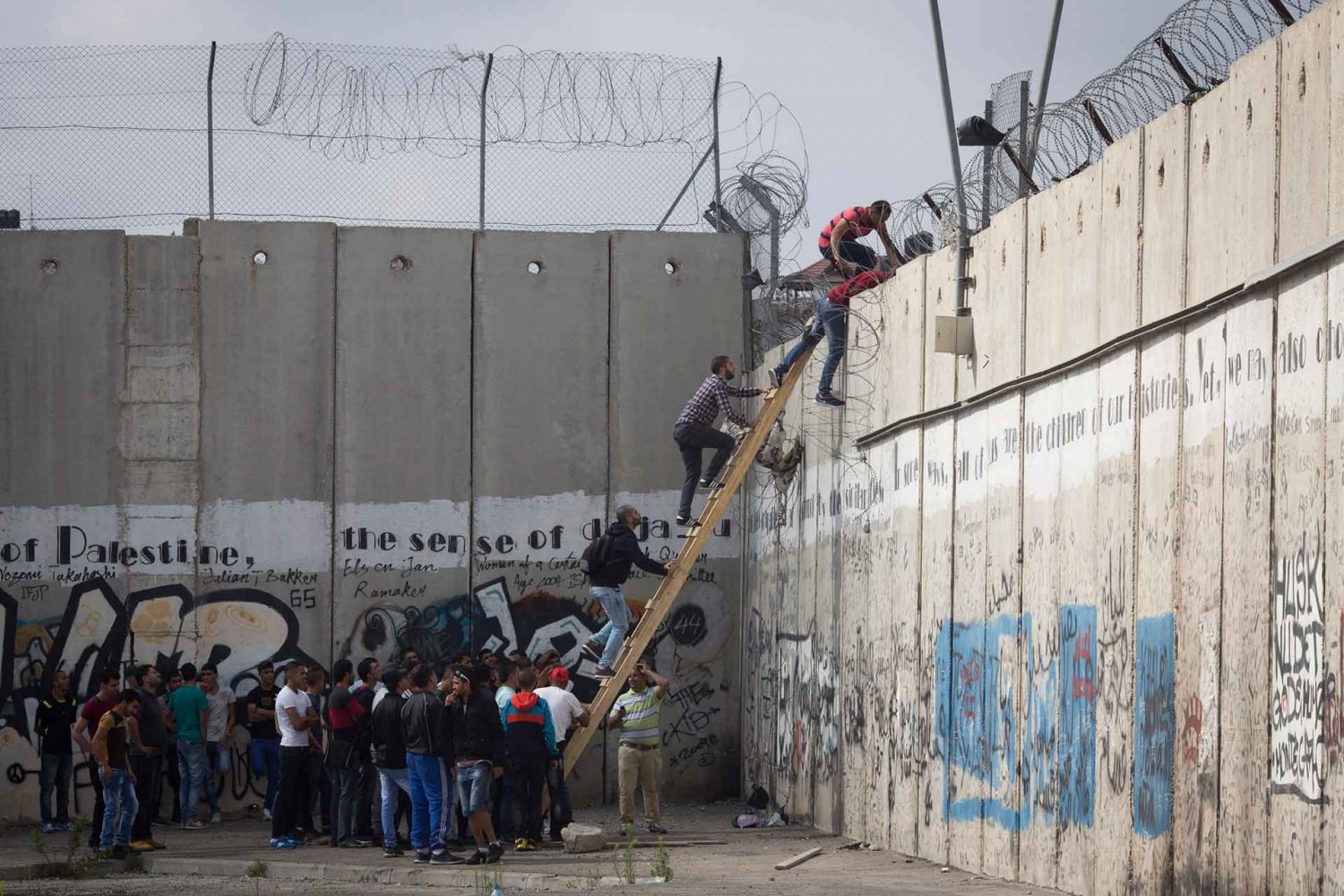 In al-Ram, Palestinians climb over the Separation Wall to reach Jerusalem
