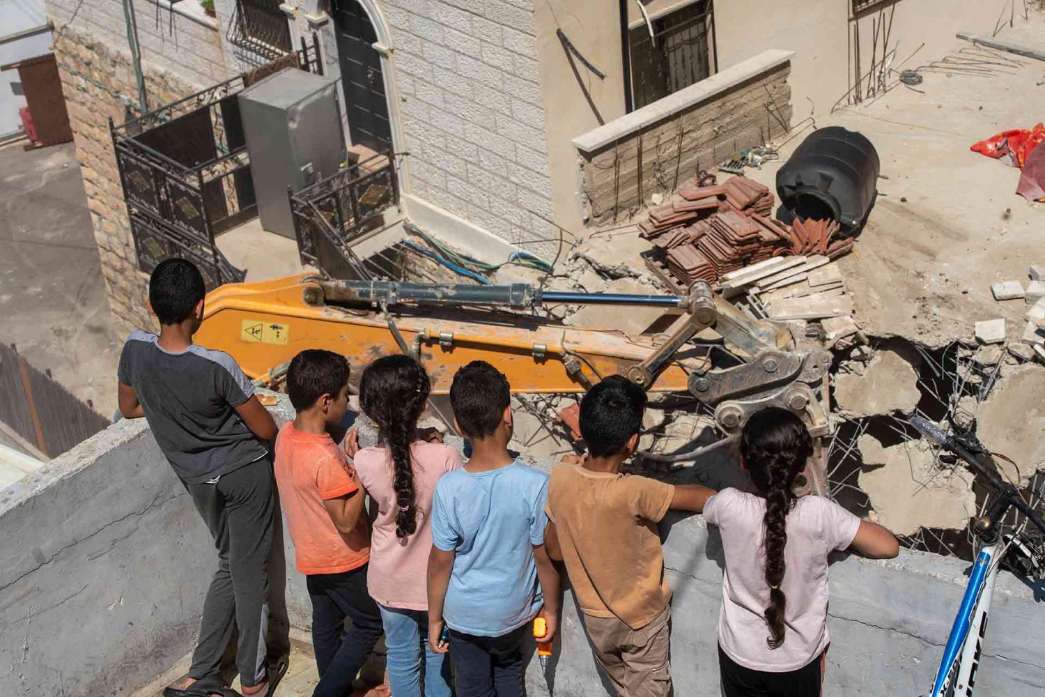 Children watching a bulldozer demolish a family home in Jerusalem