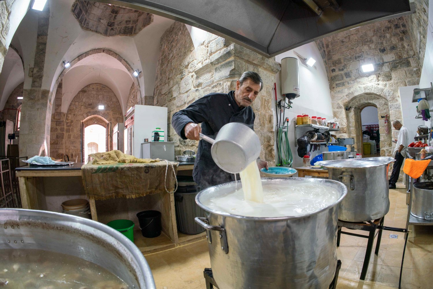 Samir Jaber stirs the yogurt sauce for mansaf in the Khaski Sultan soup kitchen in the Old City of Jerusalem
