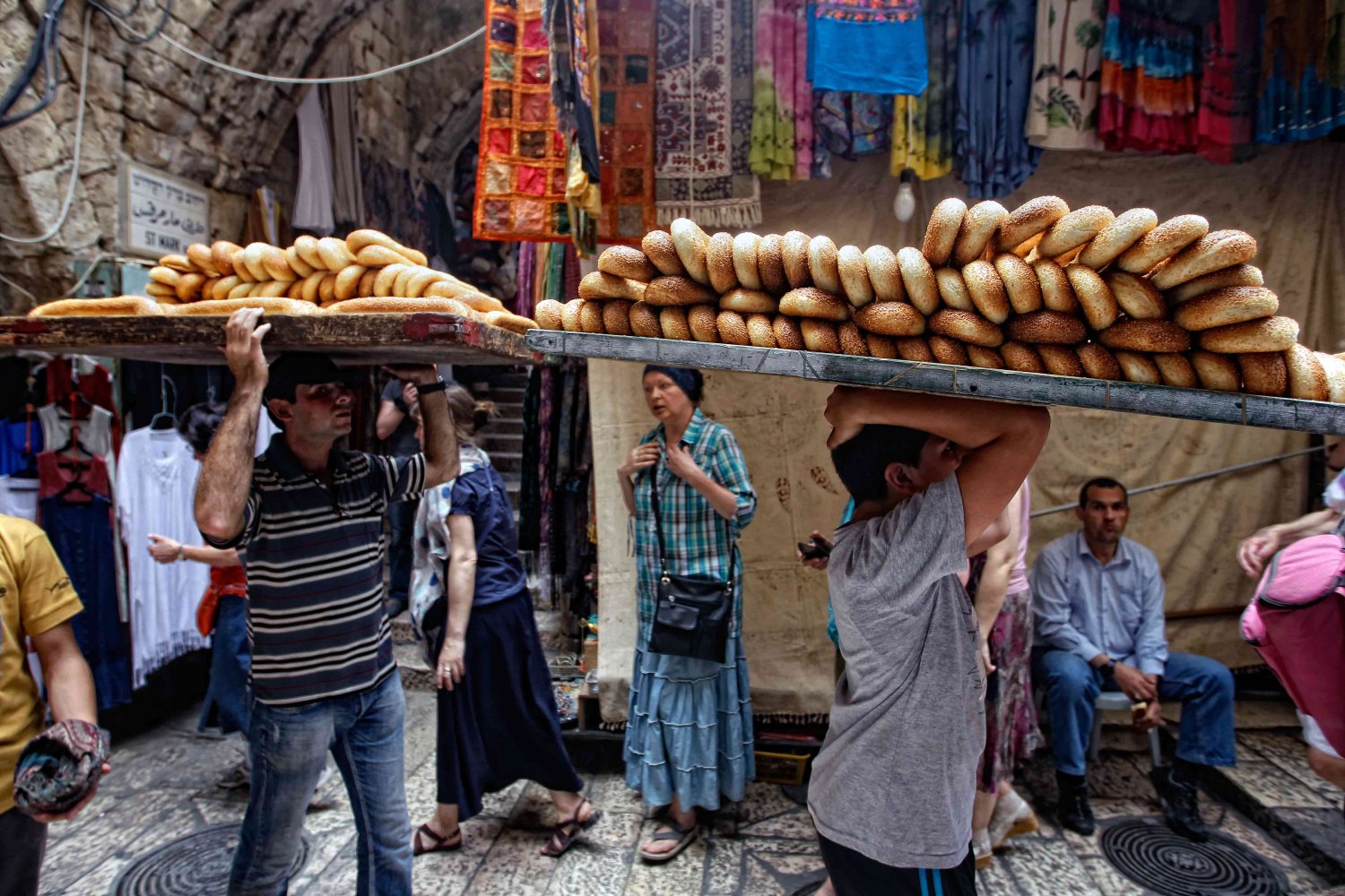 Sellers carry warm ka'ek bread from Jerusalem bakeries to buyers in Old City streets