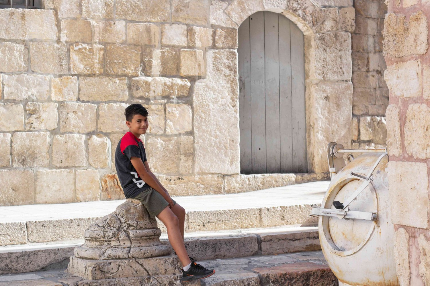 A boy rests on a well-worn ancient stone edifice in the Old City of Jerusalem, August 30, 2021.