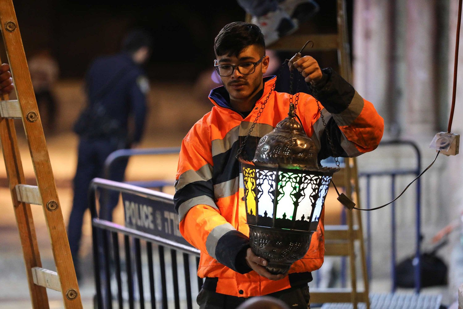 A Palestinian youth hangs a decorative Ramadan lantern or fanous in Jerusalem, 2022