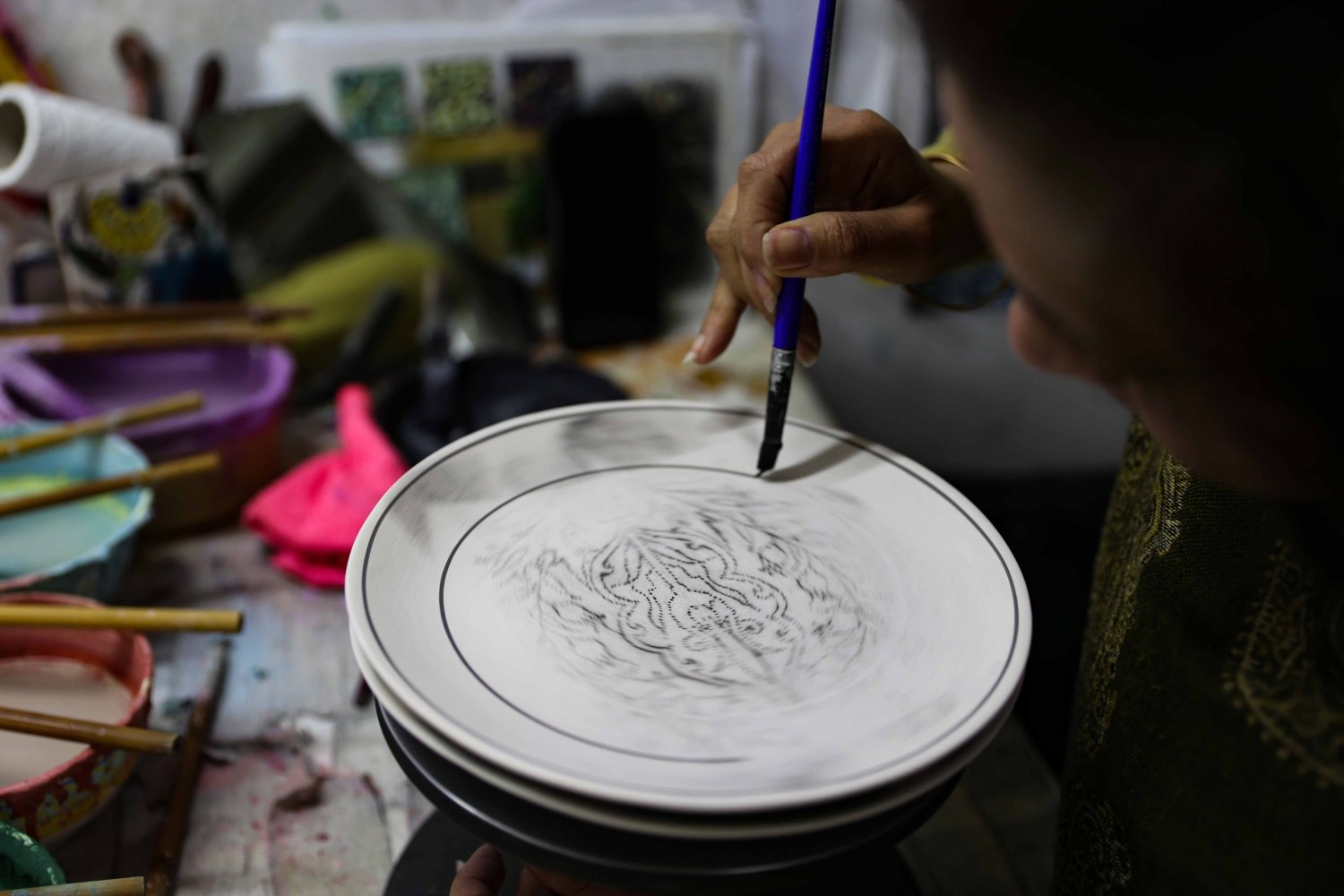 Ceramic artist Tahani al-Za‘ani outlines a design on an Armenian pottery plate at the Balian design studio 