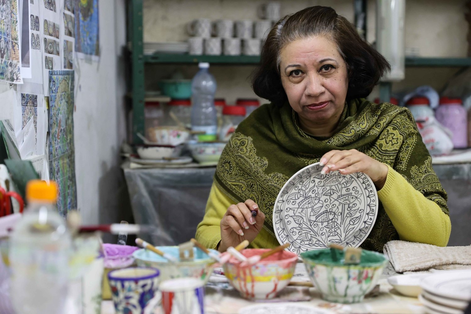A ceramic artist at Balian design studio in Jerusalem displays an Armenian pottery plate