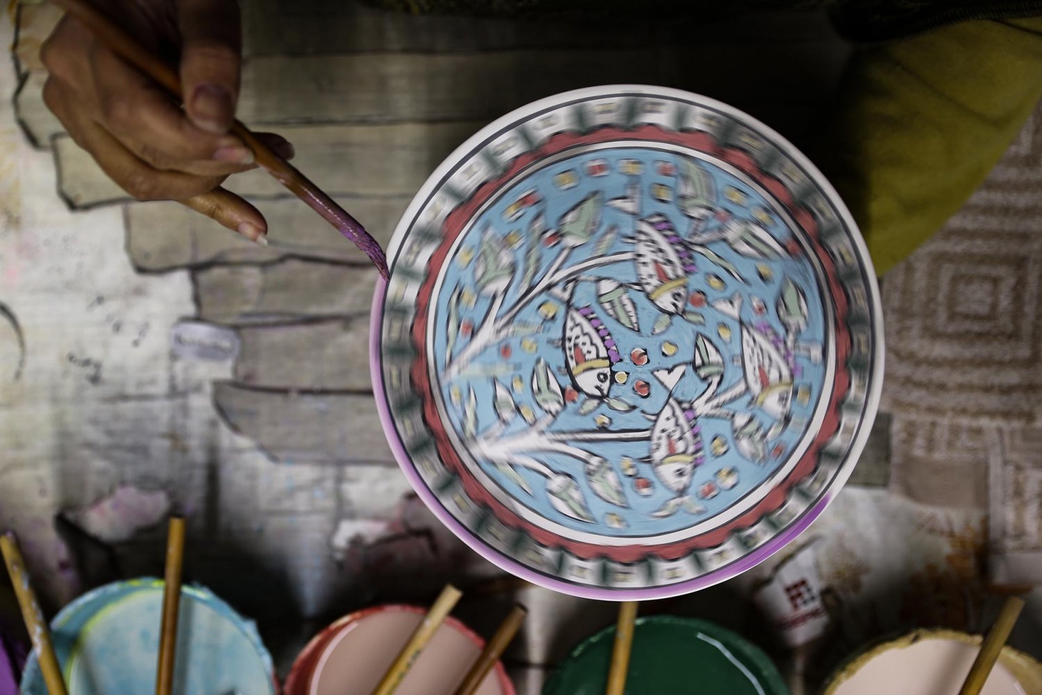 A ceramic bowl is hand-painted with a pattern of fish at the Balian workshop in Jerusalem