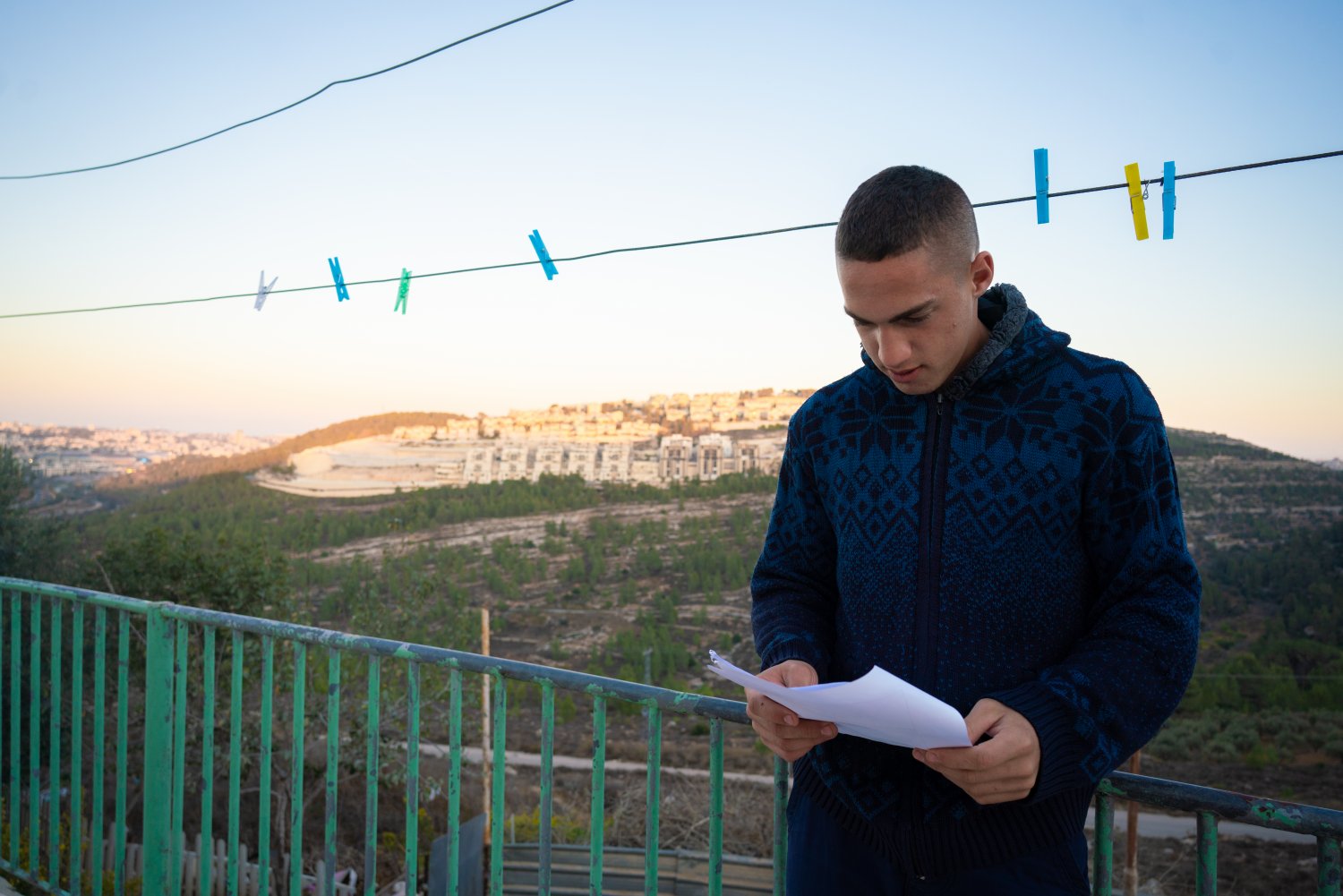 Omar Hajajla’s son, Anas, 18, studies on the ghettoized house’s balcony, with Gilo settlement visible behind him.