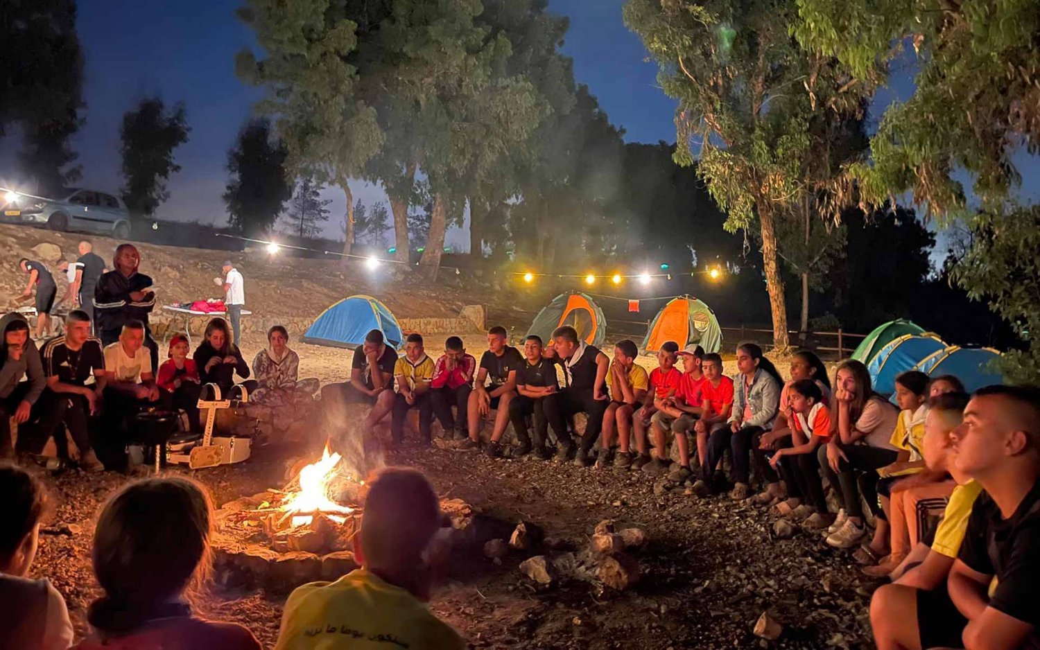 Campers enjoy a campfire party during “Silwan Summer 2022,” a youth camp for the al-Bustan district scout group