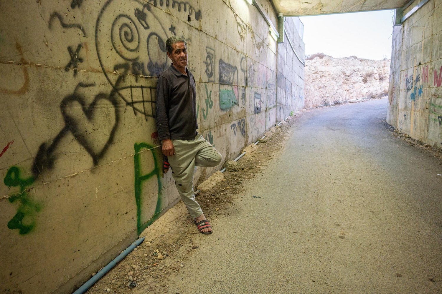 Omar Hajajla stands inside the tunnel, the only access to his ghettoized home, on the side leading to al-Walaja village.