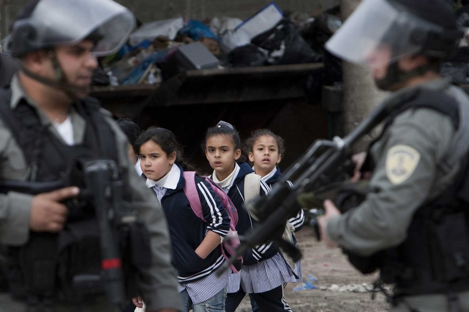 Palestinian schoolgirls walk past Israeli soldiers in Shufat refugee camp in Jerusalem, February 8, 2010.