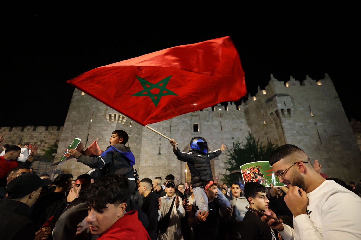 Palestinians fly a Moroccan flag at a celebration in Jerusalem of Morocco's win over Portugal at the 2022 World Cup