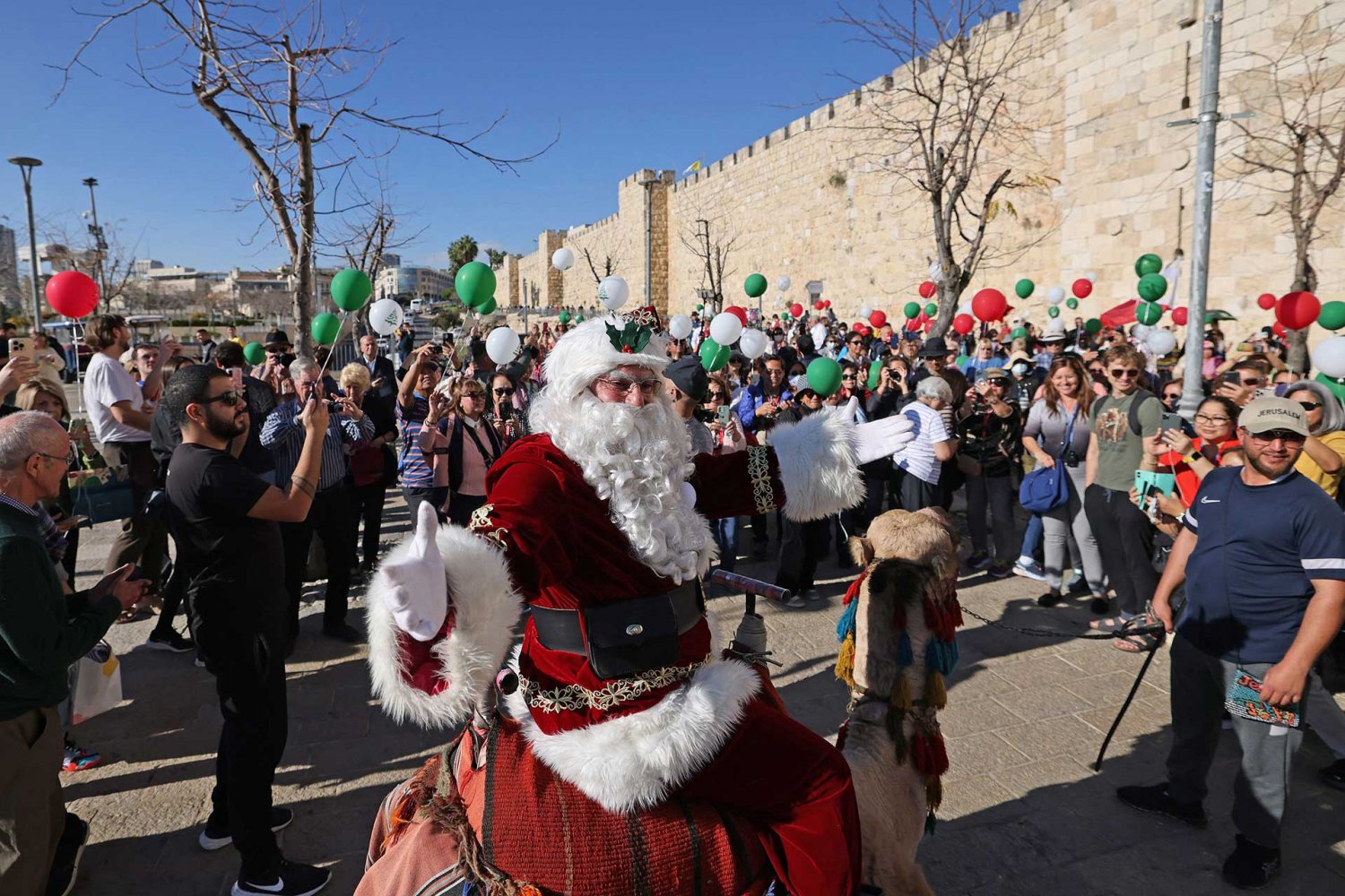 Jerusalem’s Santa Claus sits on a camel by the wall surrounding Jerusalem's Old City