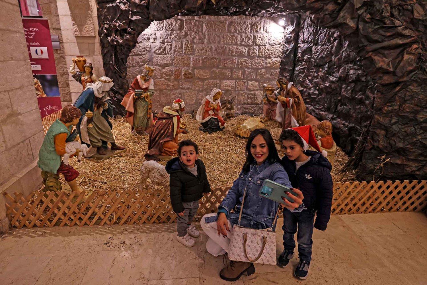 A woman and children pose for a photo before a manger scene in the Old City of Jerusalem