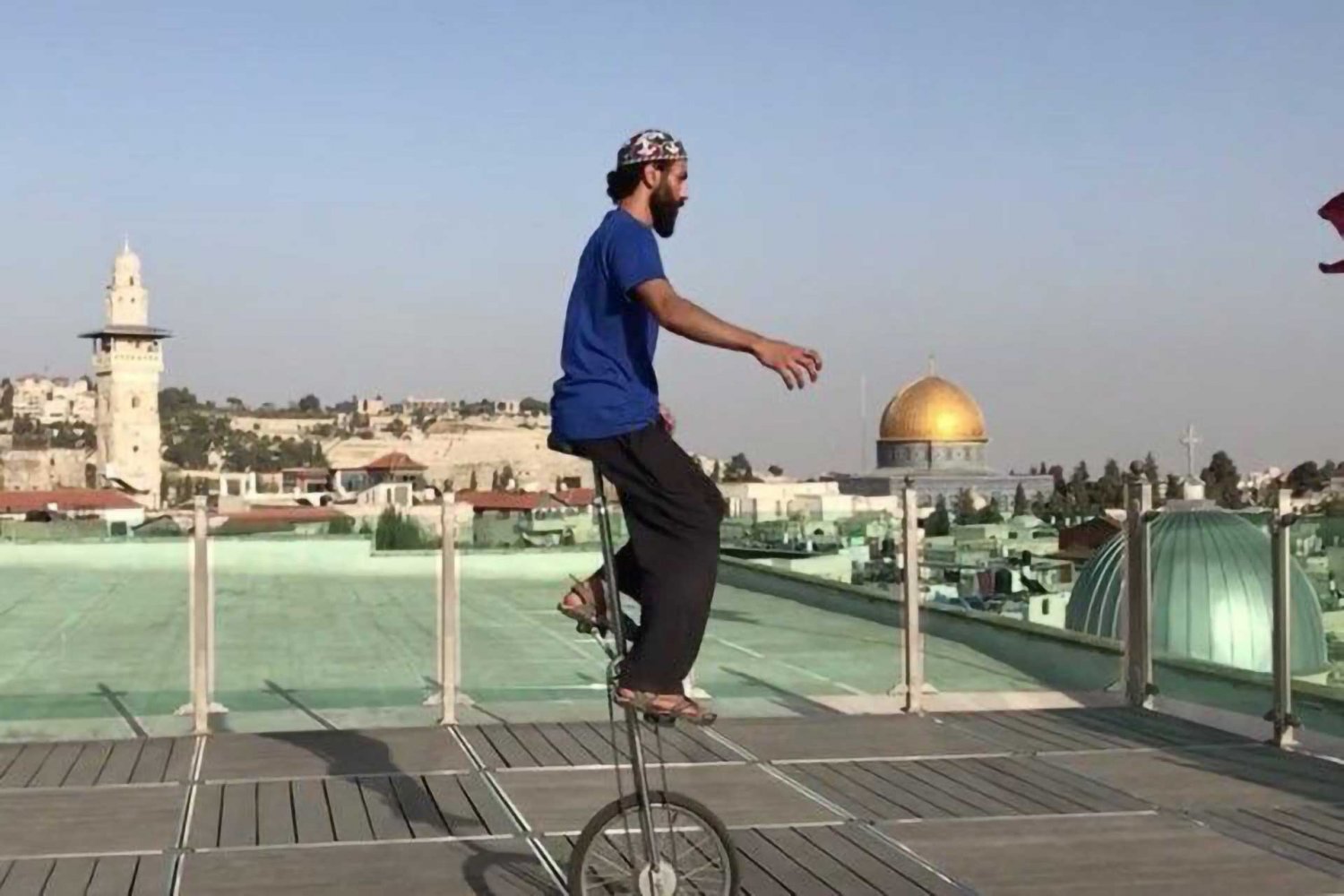 Palestinian circus artist Ahmad Ju‘beh practices with a unicycle on the rooftop of his home in the Old City of Jerusalem, with the Dome of the Rock visible on the horizon.