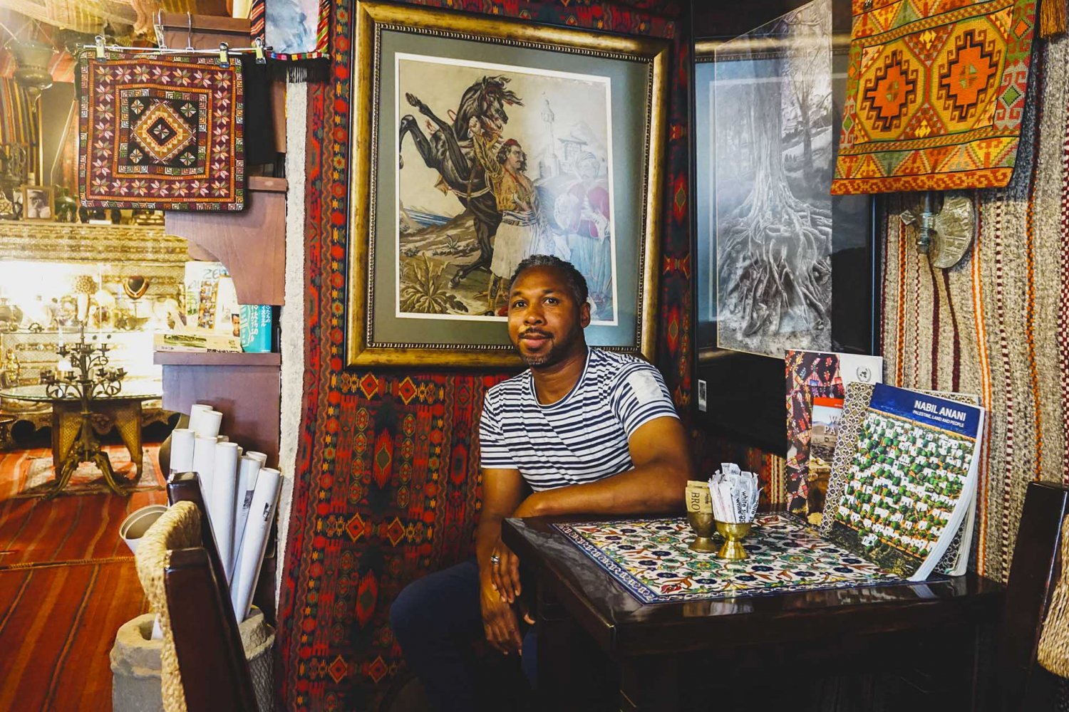 Café owner Issam Bayan sits among Palestinian artwork and tapestries that line Bassem’s Gallery & Café.