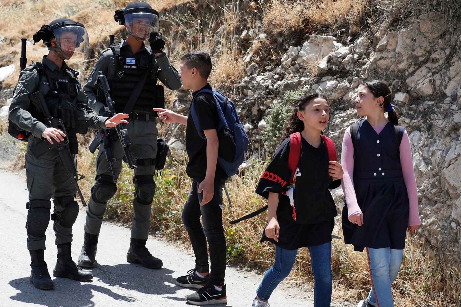 A Palestinian youth en route to school is stopped by Israeli border police near the site where Israeli bulldozers are demolishing a Palestinian house in the Palestinian east neighborhood of Silwan, May 10, 2022.