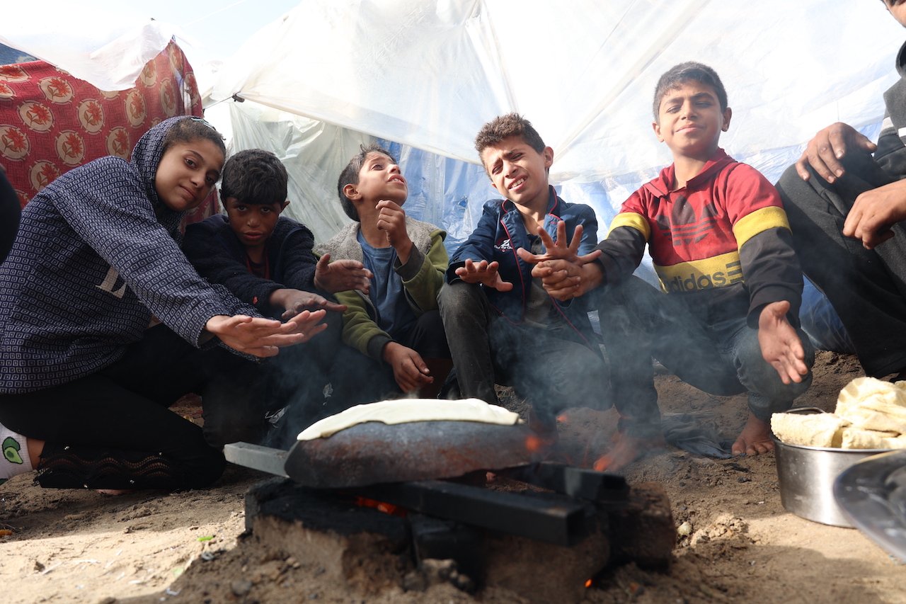 Displaced children in tents in the Gaza war seeking warmth, November 27, 2023.