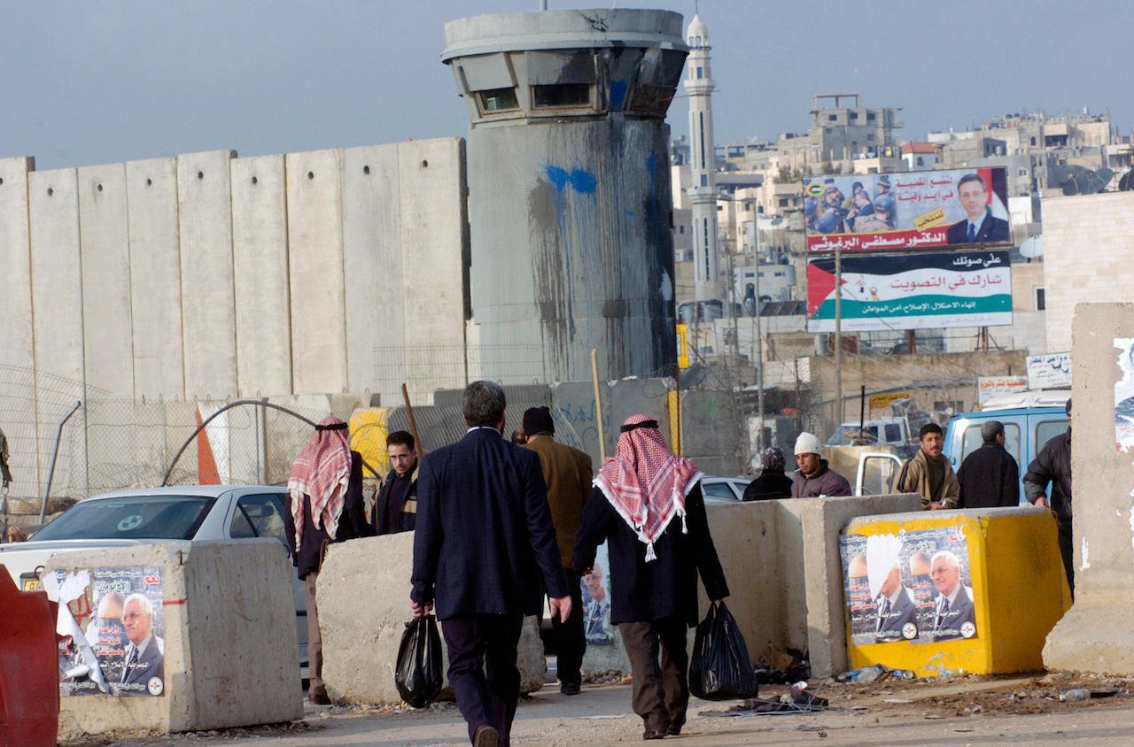 Election campaign posters against the backdrop of Israel’s Separation Wall as it’s being erected at Qalandiya checkpoint, January 7, 2005