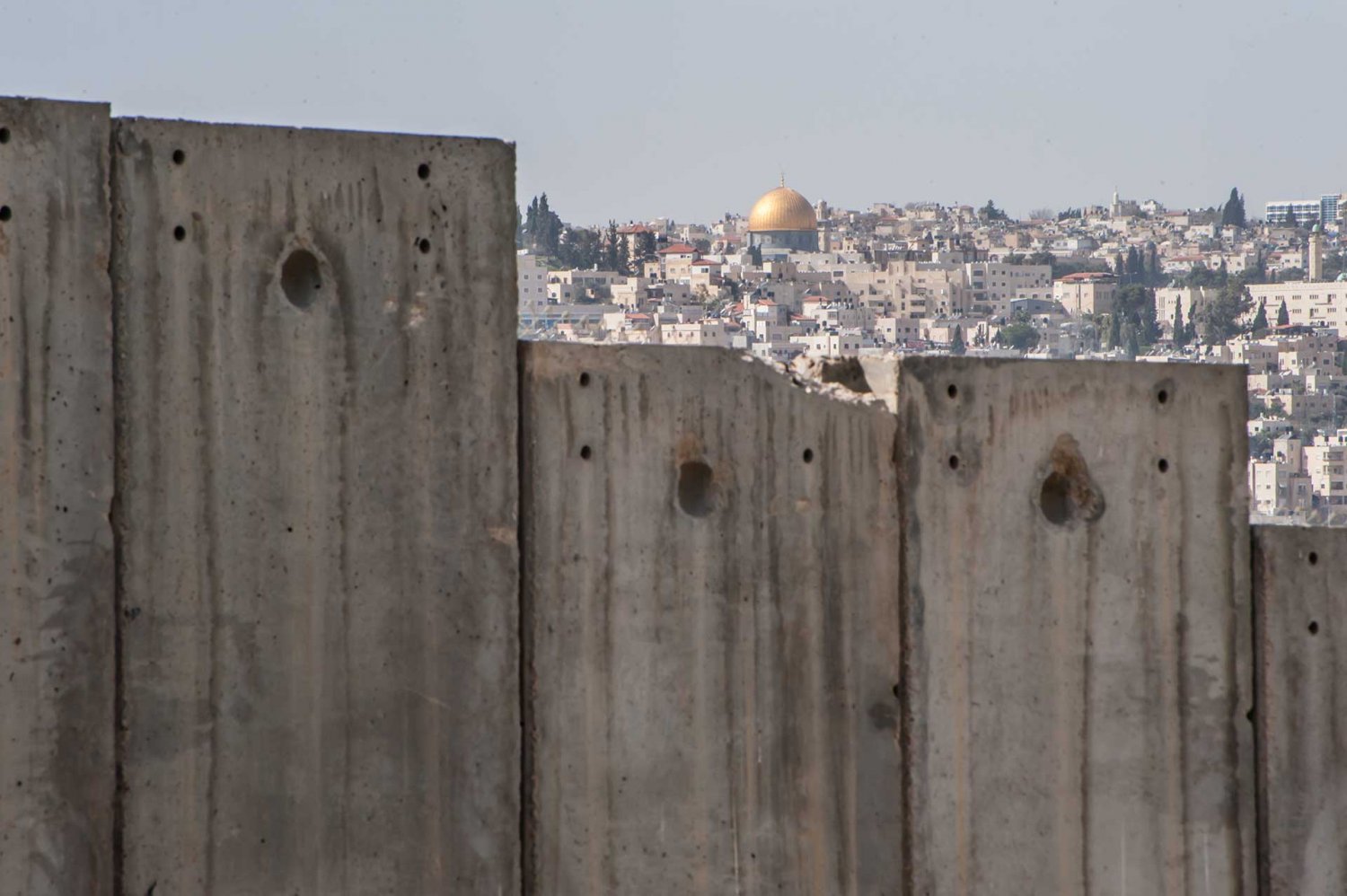 The Dome of the Rock is visible over the Israeli Separation Wall dividing East Jerusalem